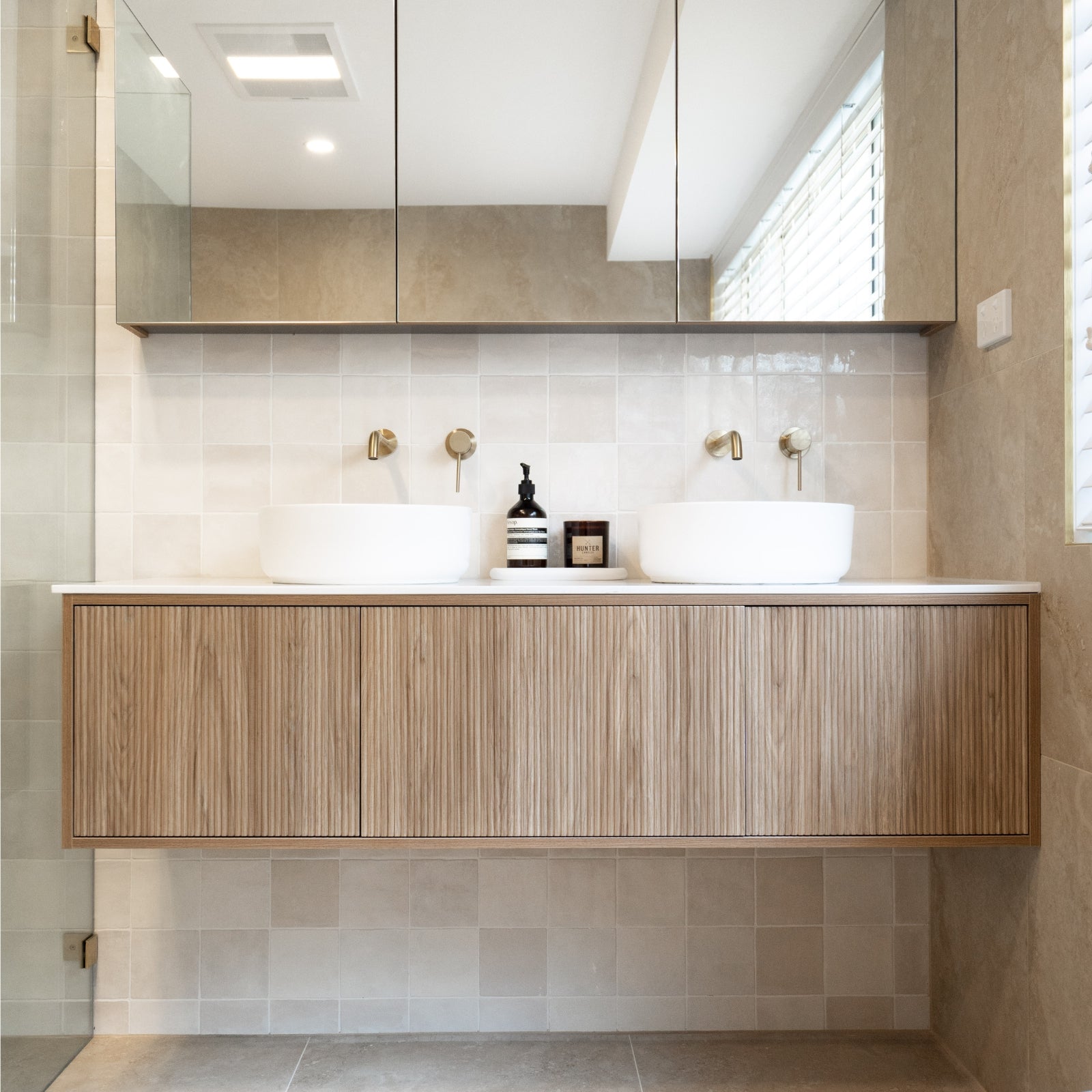 Bathroom with wooden vanity, white sinks, and tiled walls. Snow White Ella Zellige Tile 100 x 100 x 10mm Spanish Ceramic | The Blue Space