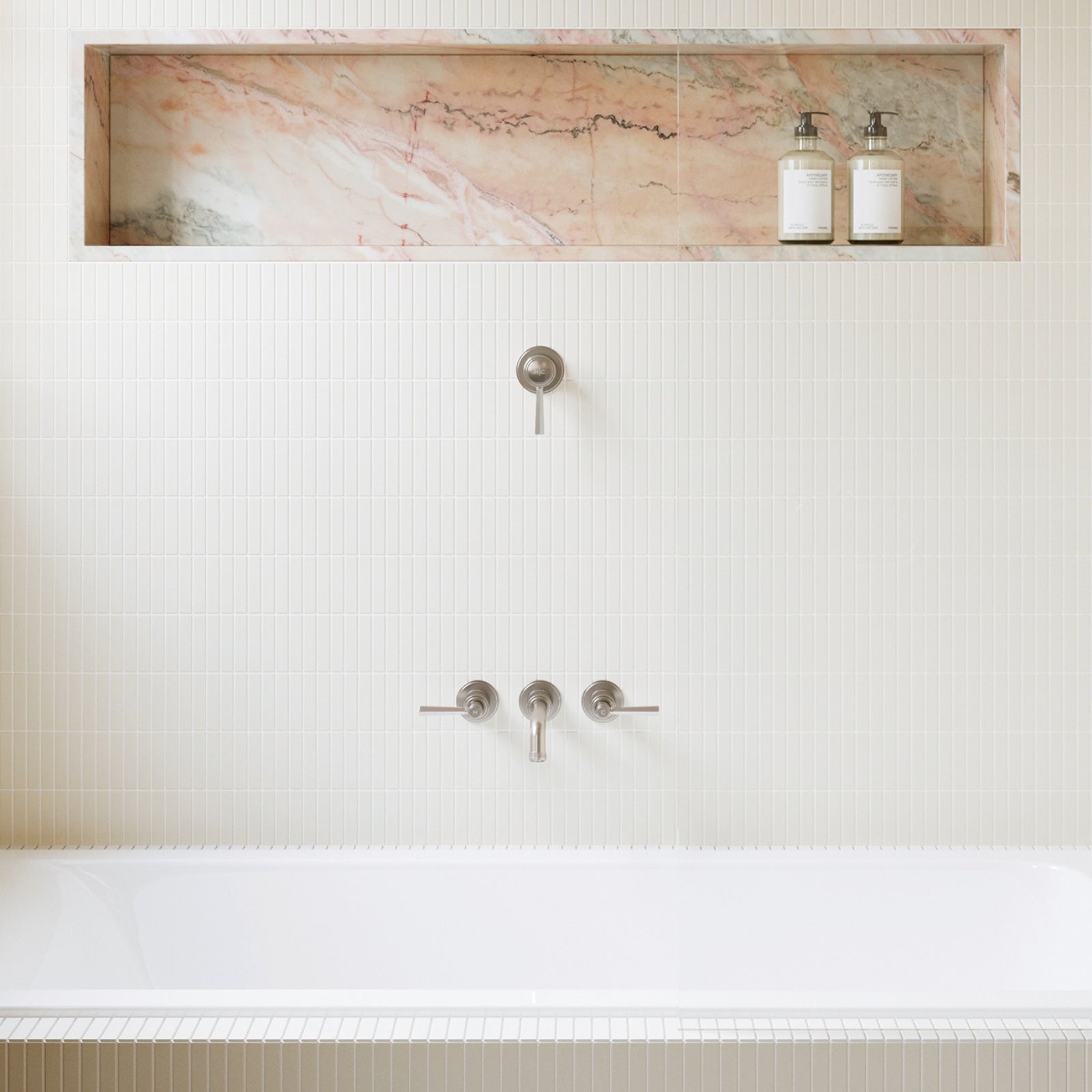 Bathroom setup with a marble shelf above a bathtub, featuring two bottles and a faucet. Phoenix Wiltern in brushed nickel - The Blue Space