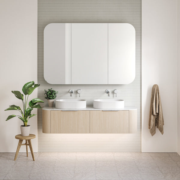 Timberline Santos Curved 1500 Double Vanity with Fluted front in Coastal Oak Woodgrain. Pictured in natural bathroom with chrome tapware and oval fluted basins - The Blue Space