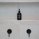 Meir Round Matte Black Wall Mixer Featured in a Bathroom with Beige Tiling