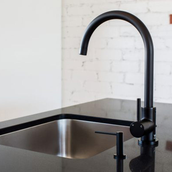 Meir Round Matte Black Soap Dispenser Featured in a Kitchen on a Black Benchtop - The Blue Space